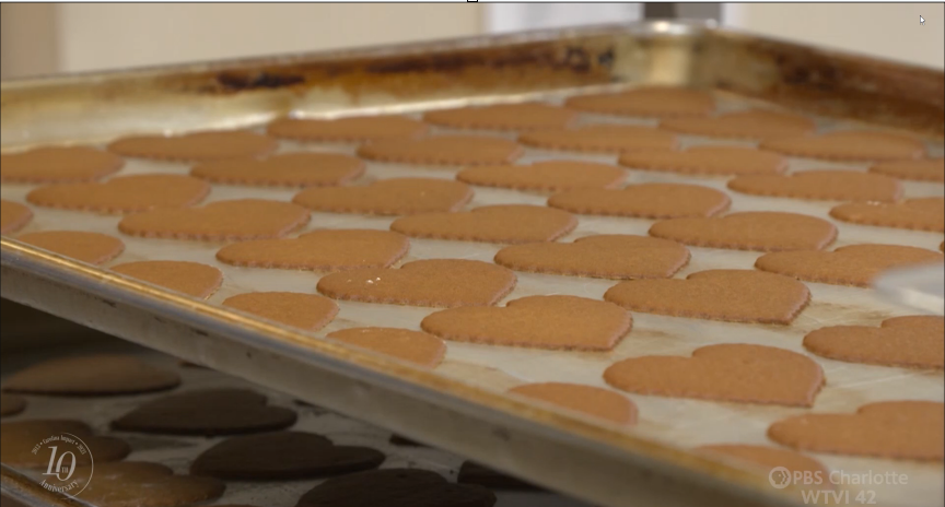 A sheet tray filled with thin, heart-shaped cookies. They are amber colored.