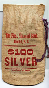 Money bag made from burlap. Bag reads "The Frist National Bank Hamlet, N.C. $100 Silver."