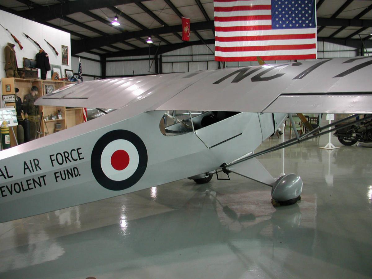 Un avión pequeño de color gris claro. Tiene un pequeño círculo rojo rodeado por un anillo blanco que a su vez está rodeado por un anillo negro. El texto visible dice "fuerza aérea" y "fondo."