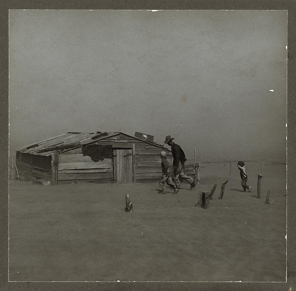 Dust storm. A father and son and their small shack are barely visible through the strong dust.