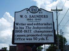 Large metallic marker that reads: "W.O. Saunders 1184-1940. Writer and editorialist. In his The Independent, 1908-1937, championed causes, promoted region. Office was 50 yds. E."