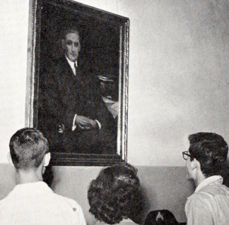 A photograph of students of Charles L. Coon High School in Wilson County looking at a portrait of Coon from the 1950 school yearbook. Image from the Wiilson County Public Library.