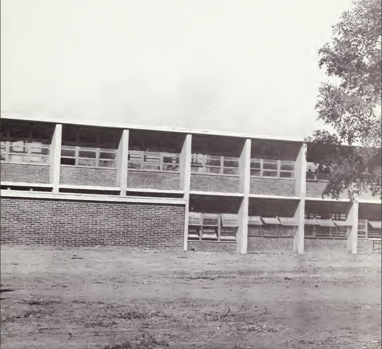 This is an image of the photo that appears on the first page of the 1966 West Charlotte High School yearbook. It shows a plain building with open windows and a lawn of dirt.