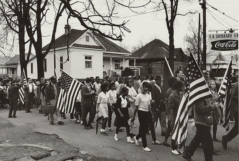 This is a photograph of demonstrators walking down a street during the civil rights march from Selma to Montgomery, Alabama in 1965.