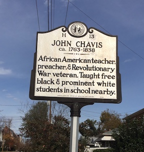 Photograph of North Carolina Highway historical marker dedicated to John Chavis. Located on Worth Street in Raleigh, NC. Reads: "African American teacher, preacher, and Revolutionary War veteran. Taught free black & prominent white students in school nearby."  The marker was erected near the site of his school in Raleigh for the 100th anniversary of his death in 1938. It was the first North Carolina highway historical marker dedicated to African American history.