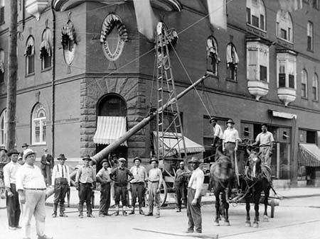 A Carolina Power and Light line crew seen posing for a photo at the corner of W. Martin and McDowell Streets in Raleigh on July 5, 1916 as they hoist up a light pole with a team of horses. From the CP&L Collection, State Archives of North Carolina. Used courtesy of the N.C. Department of Natural and Cultural Resources.