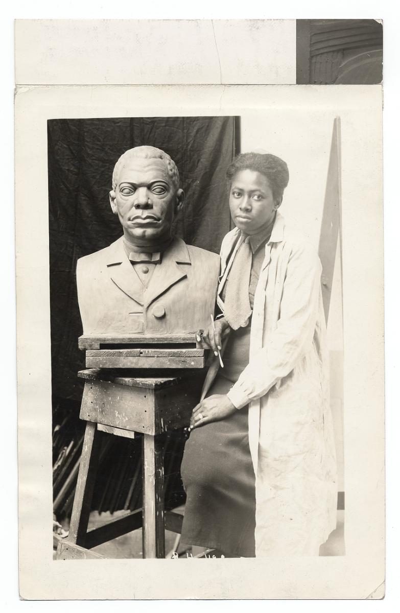 Portrait of Selma Burke seated next to her sculpture of Booker T. Washington. Taken during the 1930s while she was working for the WPA Federal Art Project. From the Archives of American Art, Smithsonian Institution.