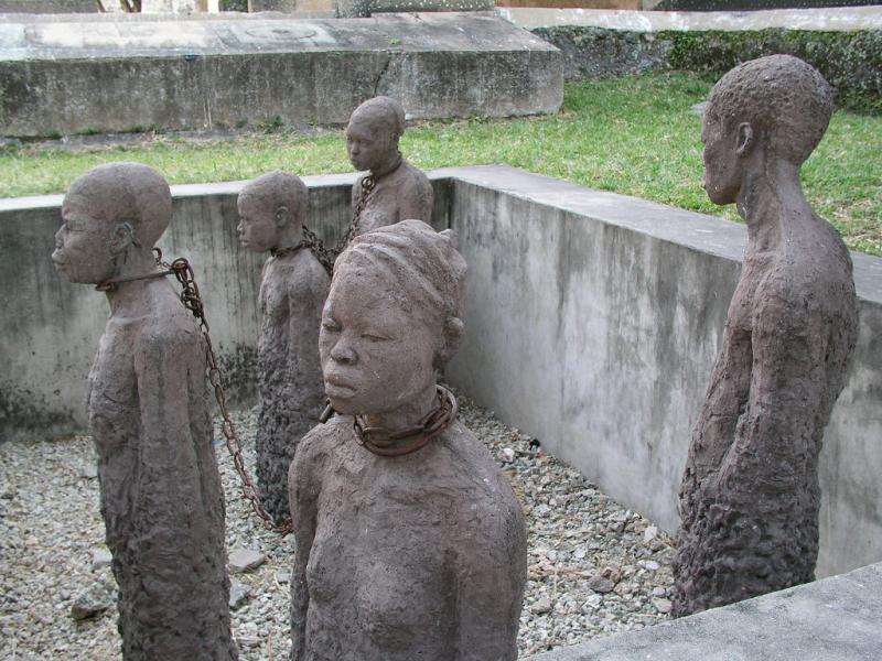 Slave trade memorial at Zanzibar. 5 states of enslaved people stand in a square. They are thin and their clothes are ragged.