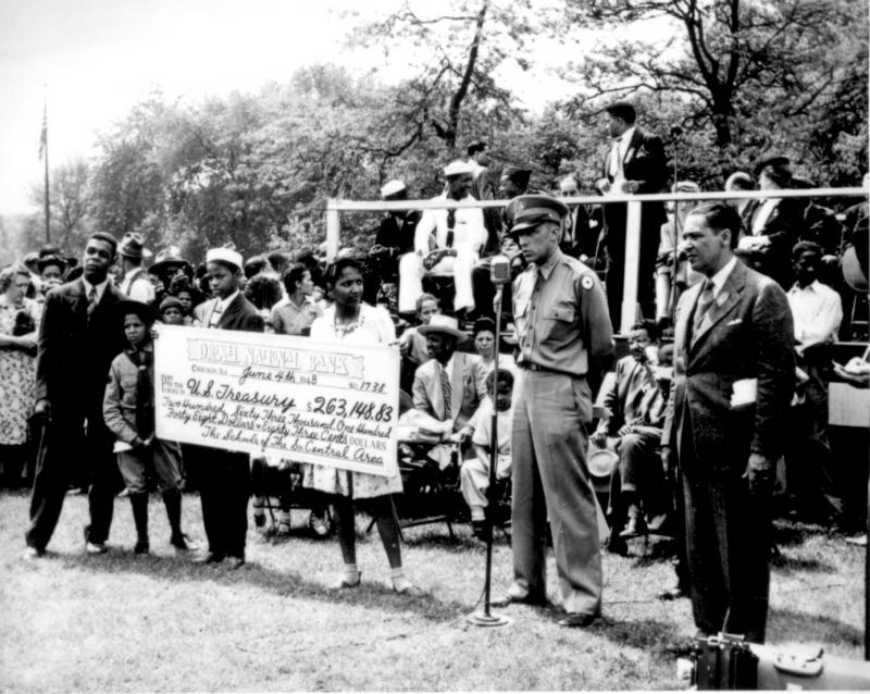 Children present a giant check to a military officer. Black and white photo.