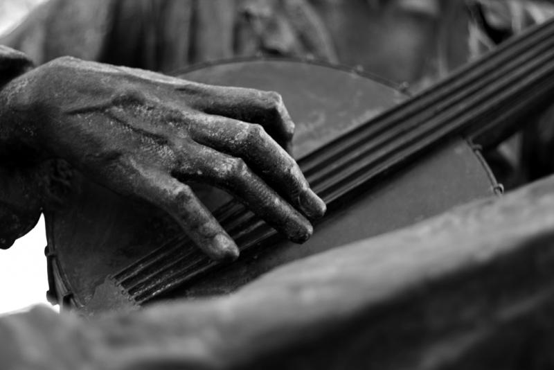 Bronze statue of a person playing a banjo. 