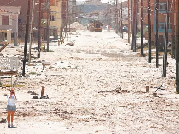 A sandy deposit lines a street. Objects and vehicles were carried by the surge.