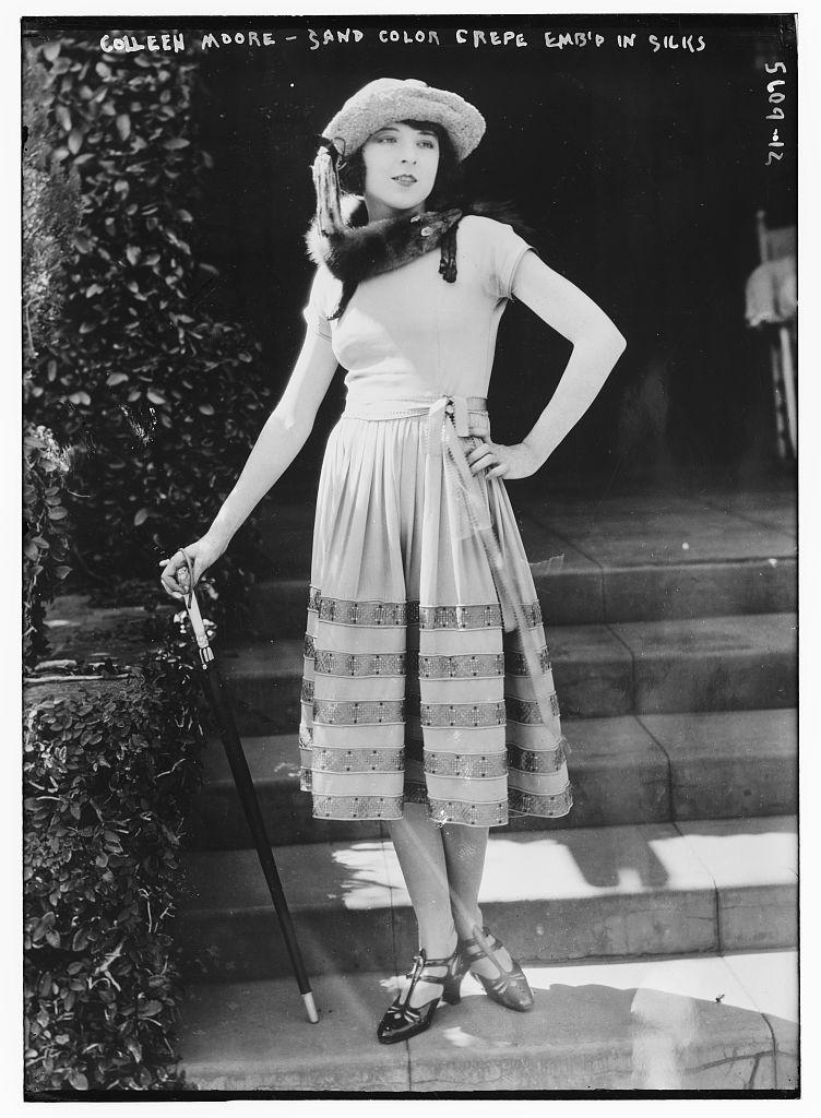 Colleen Moore. She is pictured in a dress and holding a cane with short hair.
