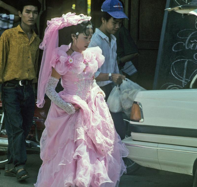 <img typeof="foaf:Image" src="http://statelibrarync.org/learnnc/sites/default/files/images/vietnam_145.jpg" width="1024" height="975" alt="Bride walks through street in lacy pink wedding dress and high gloves at Mytho" title="Bride walks through street in lacy pink wedding dress and high gloves at Mytho" />