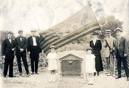 Photograph of a marker for Richard Caswell's grave, 1919. Fred A. Olds is holding the Guilford Courthouse Flag. Image from the North Carolina Museum of History.