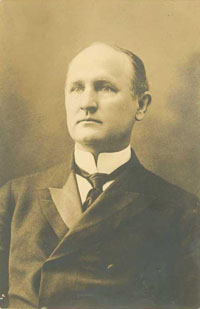 Photo of Governor Aycock. He is serious and is wearing a suit. He is balding.