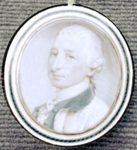 Pendant depicting Josiah Martin. He is wearing a powdered wig, and is wearing a scarf and jacket. He is smirking. 