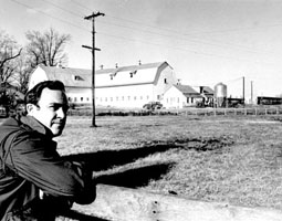 Robert Walter Scott with a farm in the background. Black and white photo.