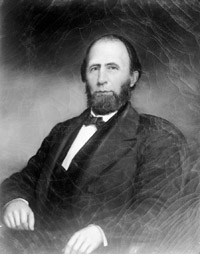 Governor Holden. He is pictured seated, wearing a suit. He is balding and has a large beard. 
