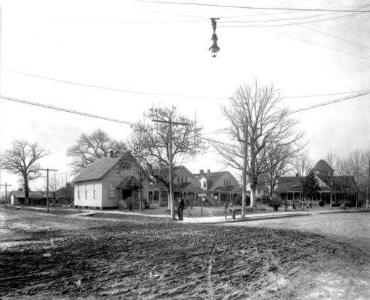 A few houses sit beside a dirt road.