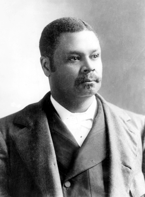 George Henry photo. He has a moustache and short hair. He is wearing a coat and vest and has a serious expression.