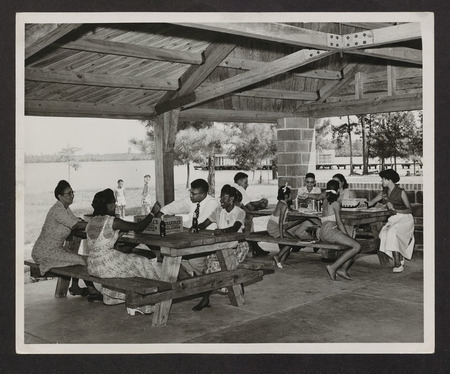 A family picnicking under a picnic shelter at Jones Lake State Park, circa 1950.