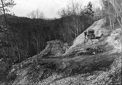 A gentleman poses for a portrait with his automobile in Hair Pin Turn, Morrow Mountain, ca. 1920. From the collection of North Carolina State Parks.