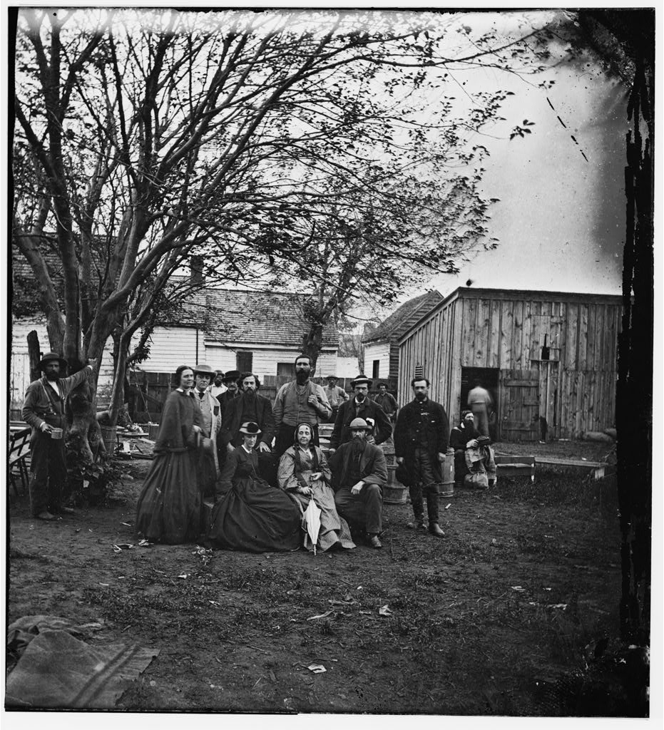 Nurses and officers of the U.S. Sanitary Commission pose under a tree in Fredericksburg, Virginia.