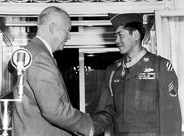 Eisenhower shaking hands with Miyamura. They are smiling. 