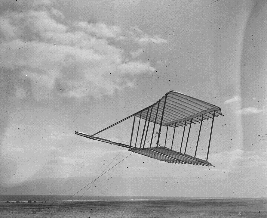 Glider above sand dunes at the beach.