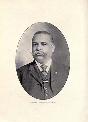 Portrait of James Hunter Young. He has short hair and a thick moutache. He is wearing a suit and is looking happy.