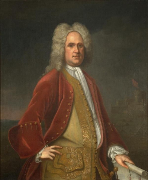 Alexander Spotswood. He is wearing a red coat and a yellow vest. His hair is tall, curly, and parted. He is grinning.