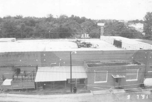 A brick building with a large section of the roof collapsed in the center.