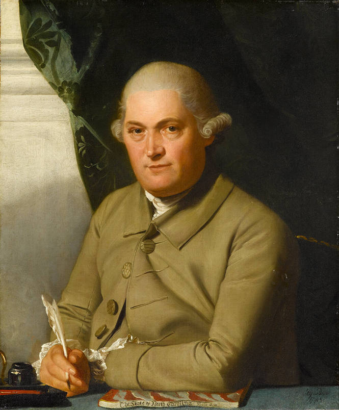 Burgwin seated at a desk. He is wearing a tan coat and holding a quill.