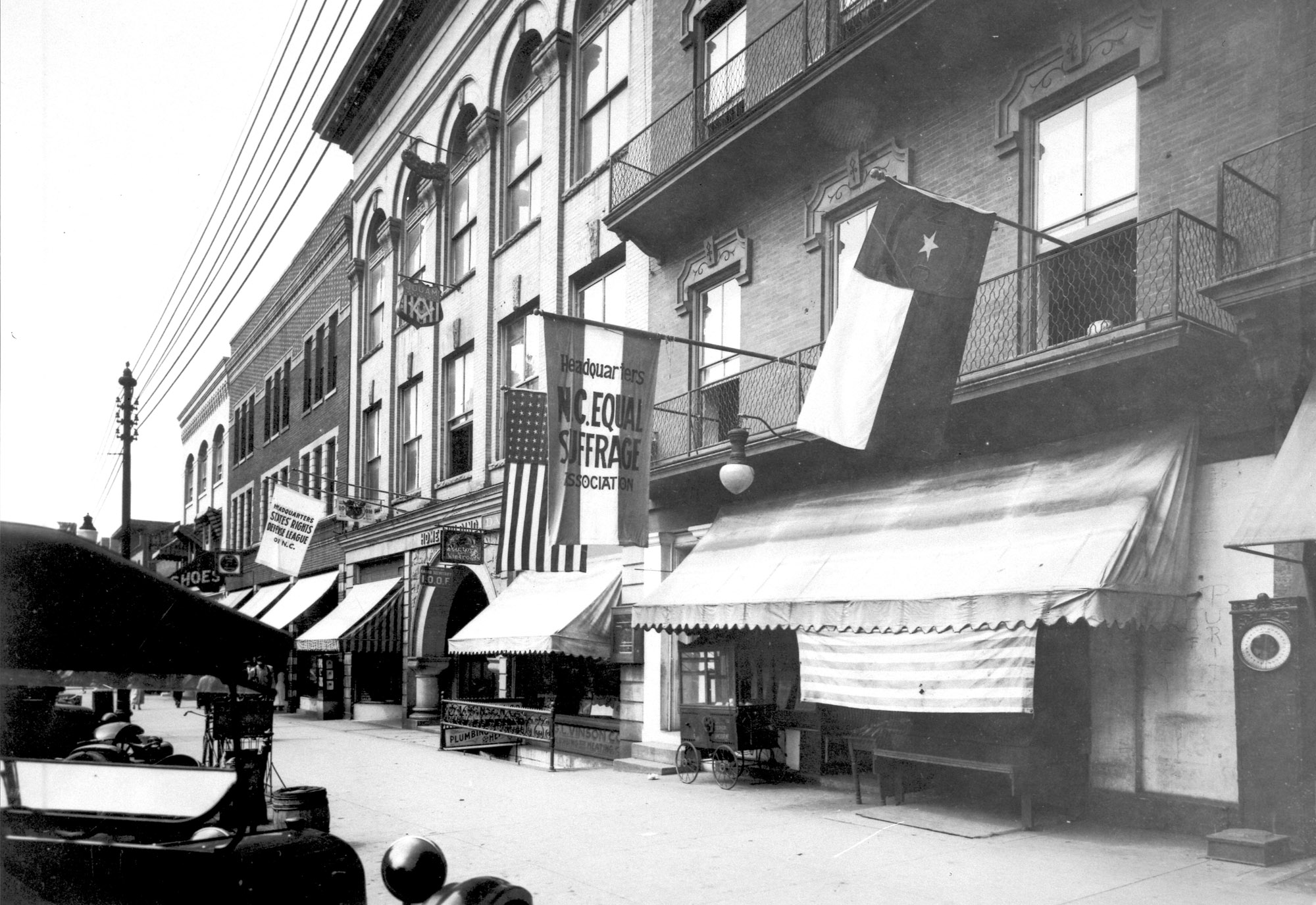 A building with a flags hanging outside, one of which reads "North Carolina Equal Suffrage Association."